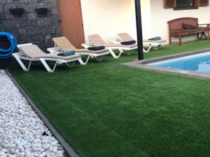 een gazon met ligstoelen en een zwembad bij Villa Altamosa in Yaiza