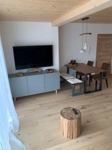 a living room with a table and a television and a table and a stump at Herzlappartment Allgäu in Wertach