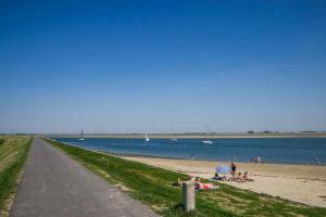 une plage avec des personnes assises sur le sable et l'eau dans l'établissement Luxe chalet 'Wysha', à Sint-Annaland