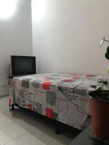 a bed in a room with a table with avertisement at Habitación privada en casa de familia cerca del CC VIVA Envigado in Itagüí