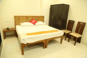 a bedroom with a bed and a cabinet and two chairs at Aamantran At Fort Maheshwar in Maheshwar