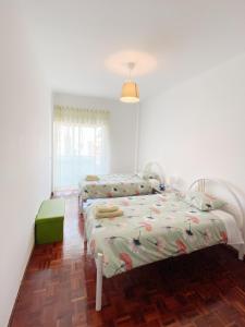 two beds in a room with white walls at apartamento na praia in Costa da Caparica