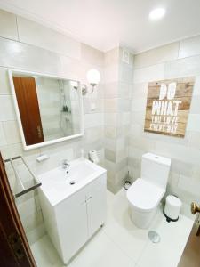 La salle de bains blanche est pourvue de toilettes et d'un lavabo. dans l'établissement apartamento na praia, à Costa da Caparica