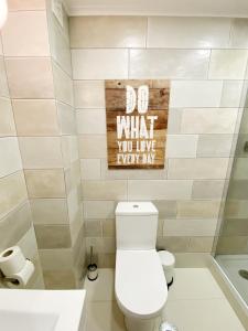 a bathroom with a toilet and a sign that says do what you live every km at apartamento na praia in Costa da Caparica