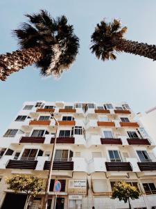a tall building with palm trees in front of it at apartamento na praia in Costa da Caparica