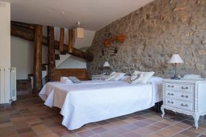 a bedroom with two beds and a stone wall at Cal Miquel de Ventolà in Ventolà