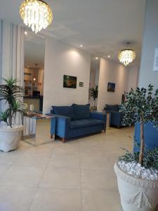 a living room with blue couches and potted plants at Hotel Real in Cabo Frio