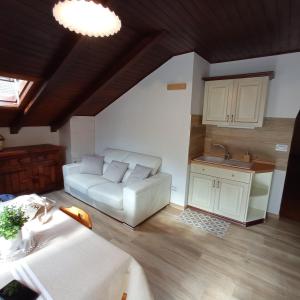 a living room with a white couch and a kitchen at La Mansarda di Sabina. in Fiera di Primiero