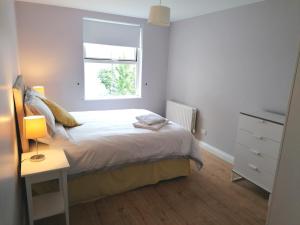 a white bedroom with a bed and a window at Derry-Londonderry city centre waterfront appartment in Derry Londonderry