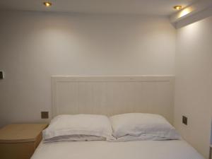 1 cama con sábanas blancas y almohadas en una habitación en Motel Schmotel, en Brighton & Hove