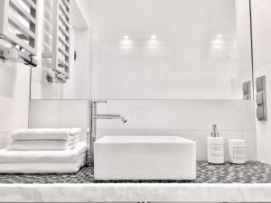 a white bathroom with a sink and towels on a counter at QuD Apartments - Poznań Centrum Andersia Square & Old Town, check in 24h in Poznań