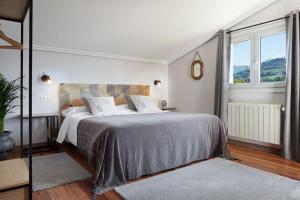 a white bedroom with a large bed and two windows at Casa Rural La Palmera - Landetxea in Lasarte