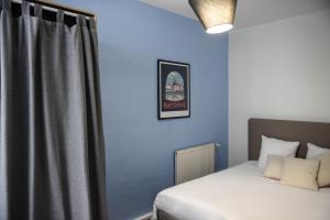 - une chambre avec un lit et un mur bleu dans l'établissement Bayonne en plein cœur Centre Historique 2 chambres, à Bayonne