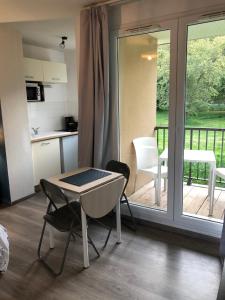 a kitchen with a table and chairs and a balcony at Studio avec piscine aux portes d’Honfleur in Honfleur