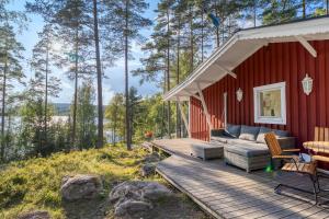 a red house with a deck with a couch at Lake cottage near Isaberg in Åsenhöga