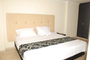 1 dormitorio con 1 cama grande con sábanas y almohadas blancas en KALINA HOTEL, en Girardot