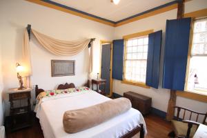 a bedroom with a large bed with blue walls and windows at Pousada Relíquias do Tempo in Diamantina