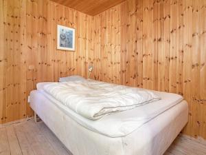Cama en habitación con pared de madera en Holiday home Væggerløse CXXXVI, en Bøtø By
