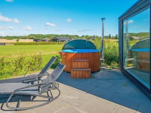 a deck with a hot tub and chairs on a patio at 10 person holiday home in Odder in Odder