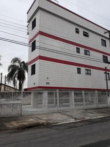 un bâtiment blanc et rouge avec une clôture à côté d'une rue dans l'établissement Apartamento com1 vaga na garagem FREE ! PRAIA GRANDE, à São Paulo