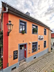 un edificio naranja con puerta roja y ventanas en charmantes Apartment Siebenschläfer über Café 7, en Weida