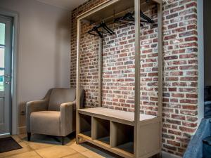 Cette chambre dispose d'une chaise et d'un mur en briques. dans l'établissement Serene Mansion in Peer with Terrace, à Peer