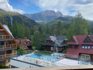 a swimming pool in a resort with mountains in the background at VIP Apartamenty ROYAL SPA in Zakopane