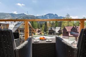 Un balcón con una mesa con un bol de fruta. en VIP Apartamenty ROYAL SPA, en Zakopane