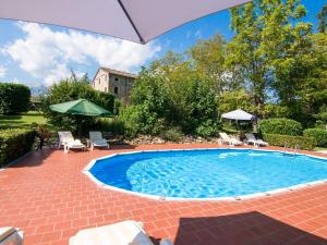 a swimming pool with an umbrella in a yard at Belvilla by OYO Fattoria 15 in Amandola