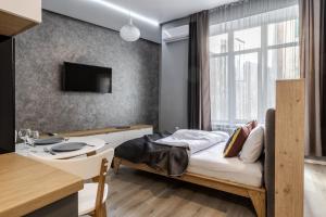1 dormitorio con 1 cama, escritorio y TV en InshiApartments on Popovycha str 3, en Leópolis