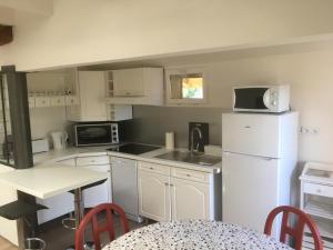 a kitchen with a white refrigerator and a table with chairs at Le Clos des May in Meylan