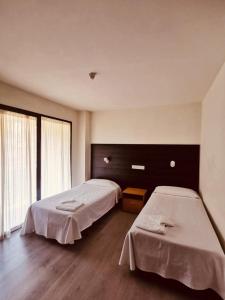 een kamer met 2 bedden en een groot raam bij Hotel Delicias in Zaragoza