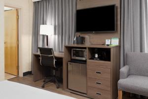 a hotel room with a desk with a television and a chair at GEC Granville Suites Downtown in Vancouver