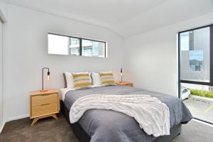 a white bedroom with a bed and a window at Salisbury Style - Brand new city apartment - Christchurch Holiday Homes in Christchurch