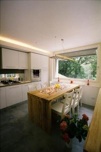una cucina con tavolo in legno e armadietti bianchi di Varesello 20 a Brunate