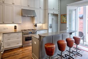 a kitchen with white cabinets and a island with bar stools at Liberty Street Redbrick Town and Carriage House in Savannah