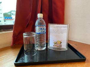 - un plateau en plastique avec une bouteille d'eau et un verre dans l'établissement Hotel Deleeton, à Kota Kinabalu