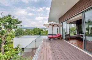 een huis met een houten terras met een paraplu bij BOM HOMES- FLAMINGO ĐẠI LẢI resort in Ngọc Quang
