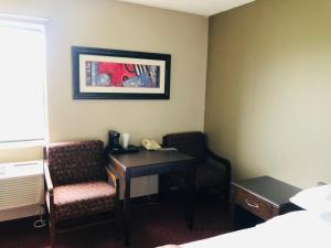 a hotel room with a desk and chairs and a phone at Super 8 by Wyndham Omaha SW in Omaha