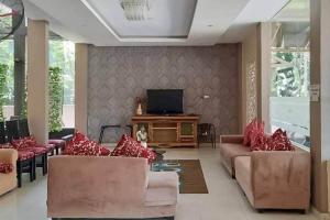 a living room with couches and a flat screen tv at Pakansari Guest Inn Mitra RedDoorz in Bogor