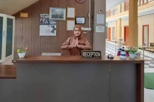 Eine Frau steht hinter einem Empfangsschalter in der Unterkunft Pakansari Guest Inn Mitra RedDoorz in Bogor