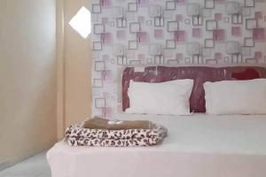 1 dormitorio con 1 cama con pared y fotografías en Pakansari Guest Inn Mitra RedDoorz, en Bogor