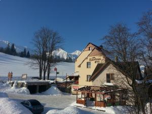 a building with snow on the ground next to at Penzion Ždiaran in Ždiar