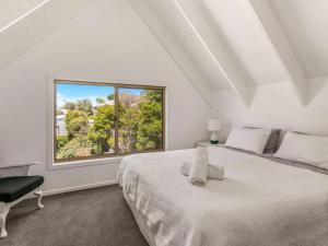 a bedroom with a white bed and a large window at A la Plage in Cape Woolamai