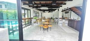 a dining room with tables and chairs and windows at Stay Here Hostel in Chiang Mai