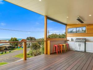 an open deck with a kitchen and stools at Waikiki Views in Smiths Beach