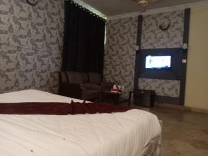 a bedroom with a bed and a chair and a television at Casa Grande in Islamabad