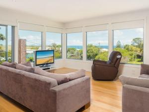 sala de estar con sofá, TV y ventanas en Waikiki Dream, en Smiths Beach