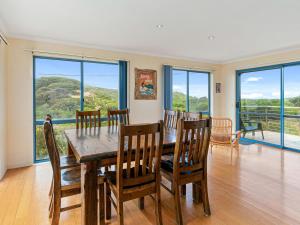 a dining room with a table and chairs and windows at Adnajur in Surf Beach