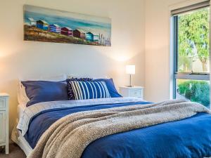 a bedroom with a blue bed with a painting on the wall at The Shack in Cowes